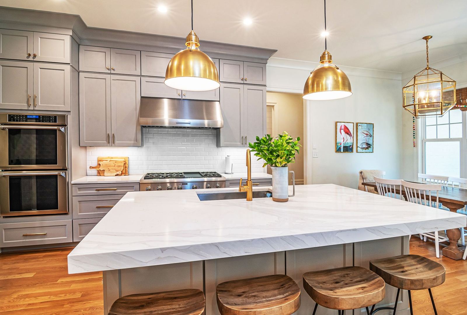 Bright kitchen with a white island, brass pendant lights, and wood floors
